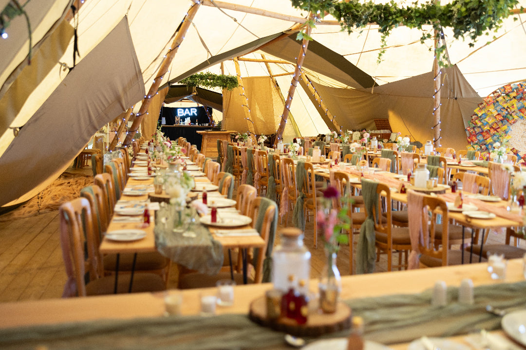 Dining setup inside a large tent with tables, chairs, and decorative elements.